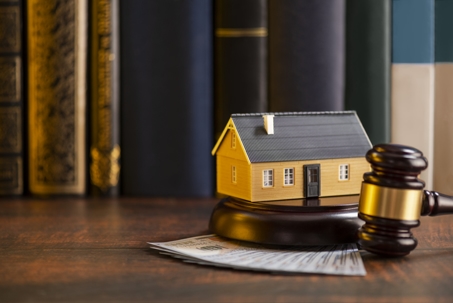 a model of a house, a gavel, and money